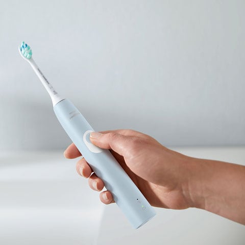 Person turning on an electric toothbrush