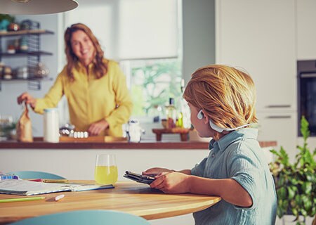 Boy watching video while using Philips open-ear wireless kids headphones